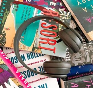 Mother's day gift ideas- audiobook subscription. photo is Gray Beats headphones sitting on a pile of books